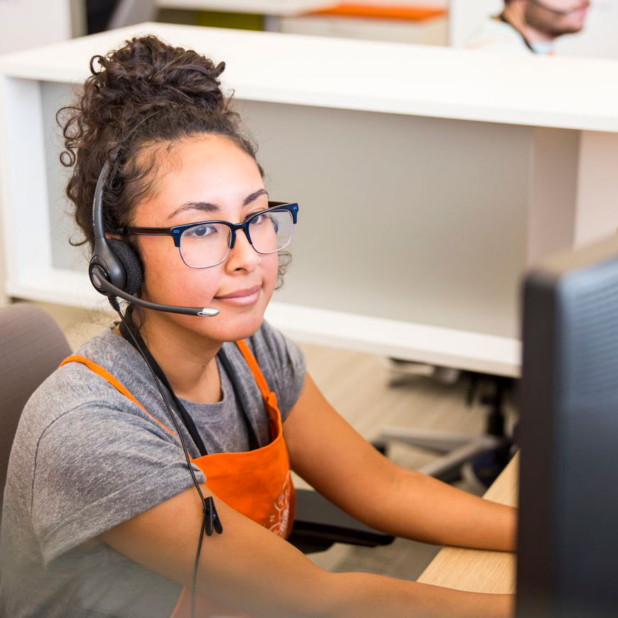 Young woman in Home Depot apron and headset takes support call