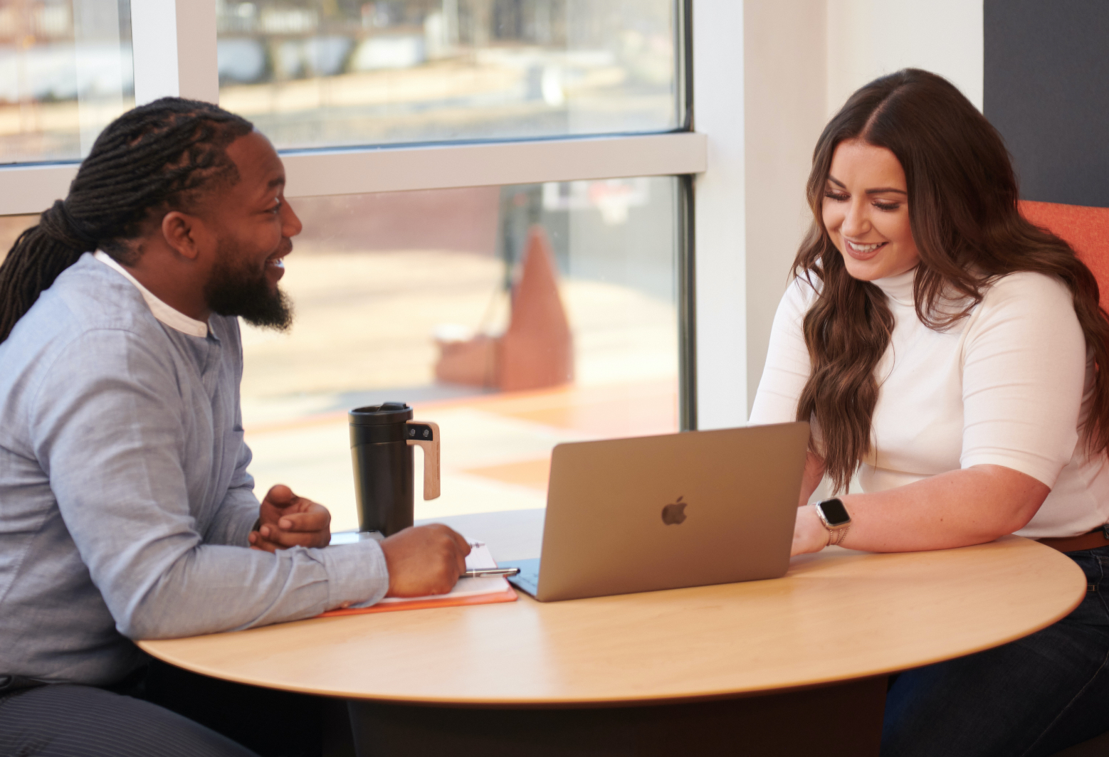 Two corporate employees look over something on a mac together.